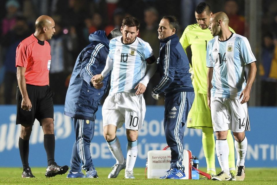 Javier Mascherano and Sergio Romero look on as Lionel Messi receives treatment for a slight knock 