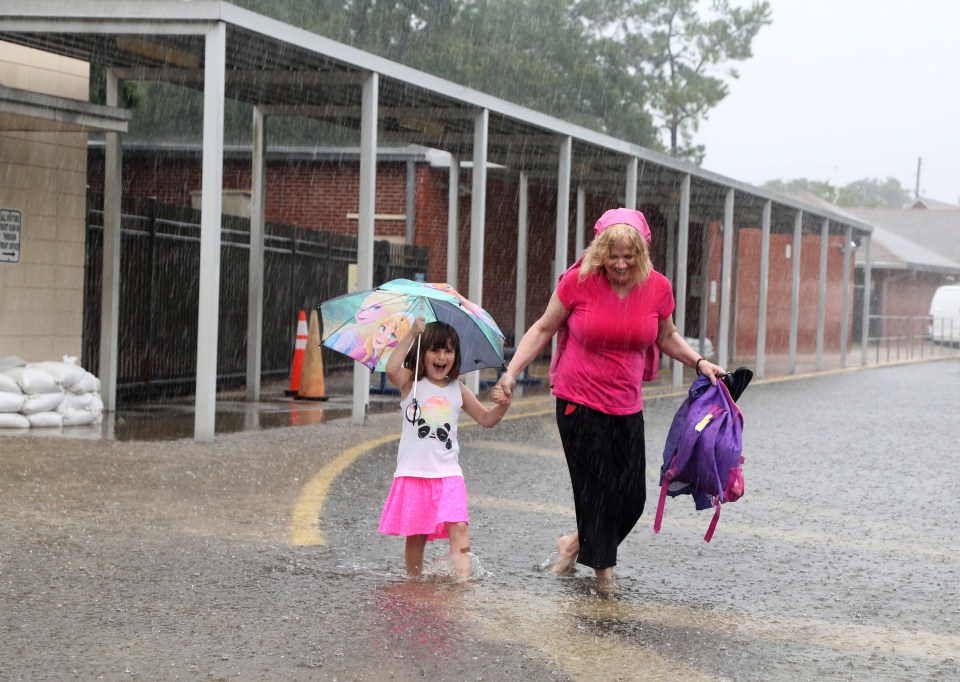 Ariel Callahan, 5, left, and her grandmother Kelly Smith, navigate rain water