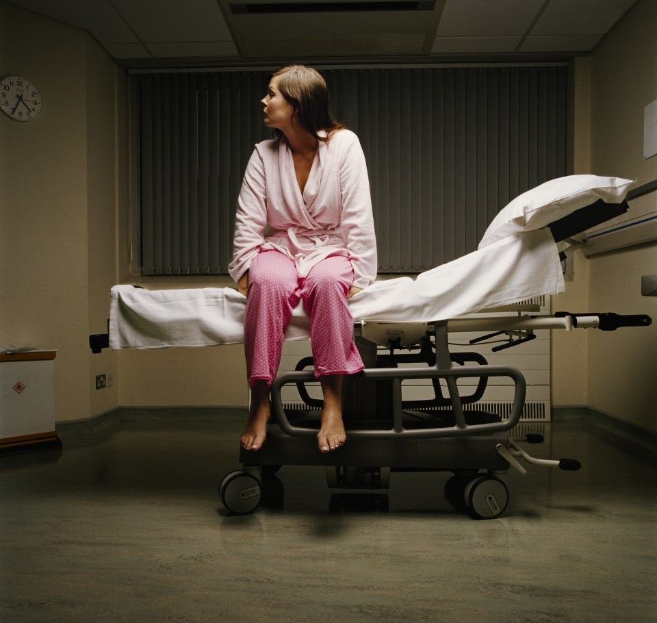 Young female patient sitting on edge of hospital bed