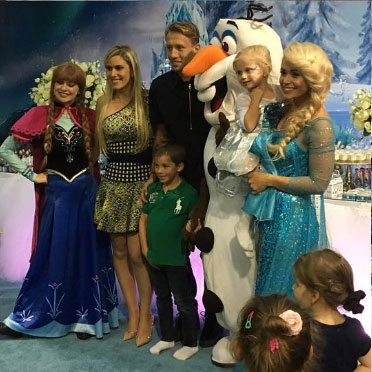 Lucas, his daughter, and his family pose with characters from Disney's Frozen