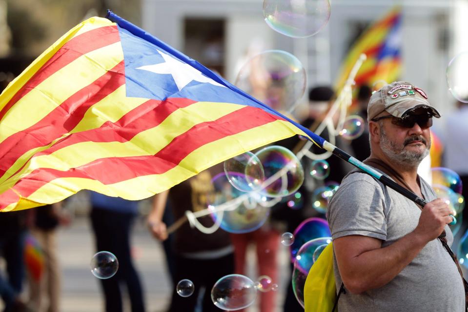 A man with Catalonian flag walks near the Arc de Triomf