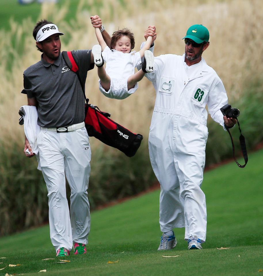 Bubba Watson of the US (L) and Webb Simpson's caddie Paul Tesori (R) hoist Tesori's son Isaiah in the air on the fifth hole during the Par 3 Contest