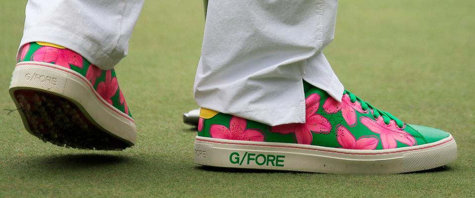 Bubba Watson of the US wears green sneakers with pink Azaleas on them from a companby called 'G/Fore' as he plays on the fifth hole