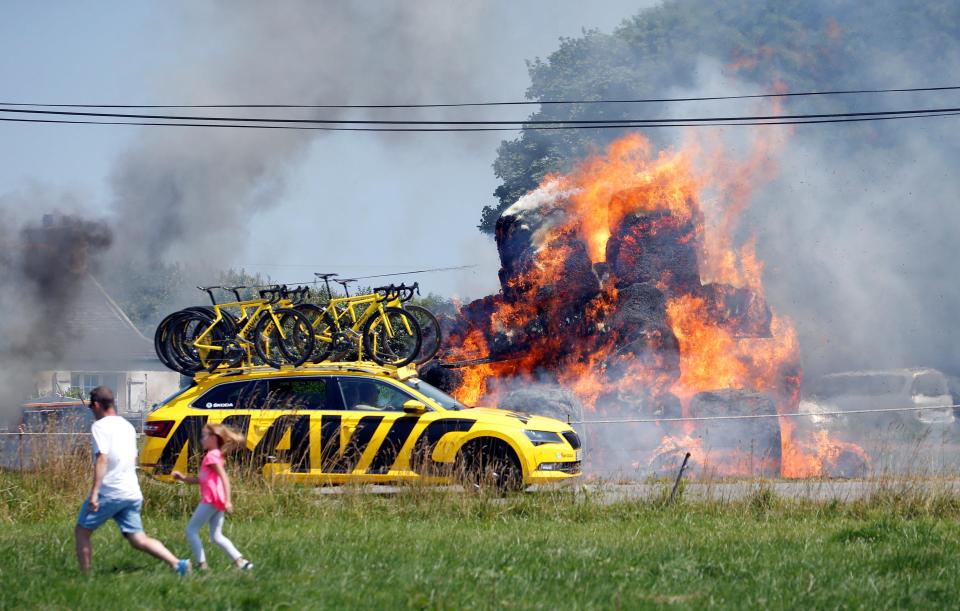 The Mavic neutral service car drives past the fire as the world's biggest bike race rolls past
