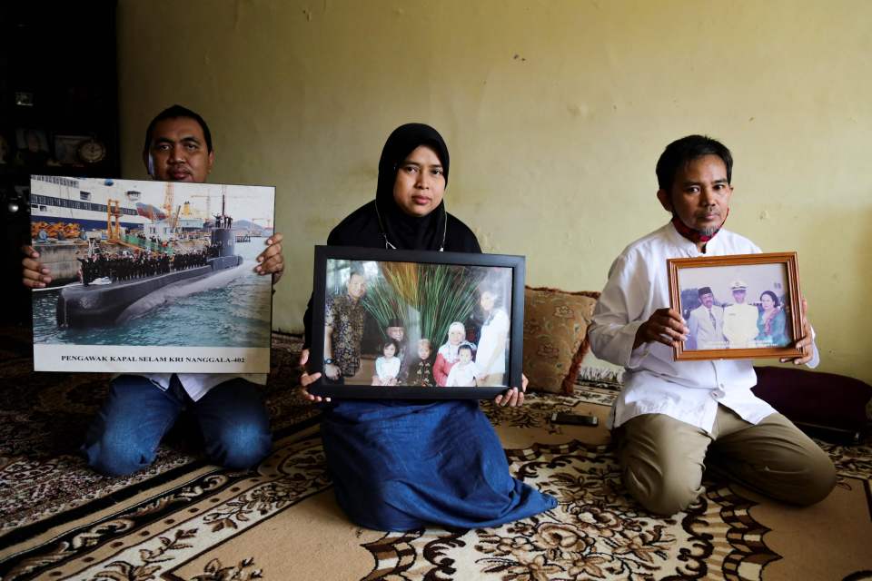 Relatives of those on board hold up pictures of them