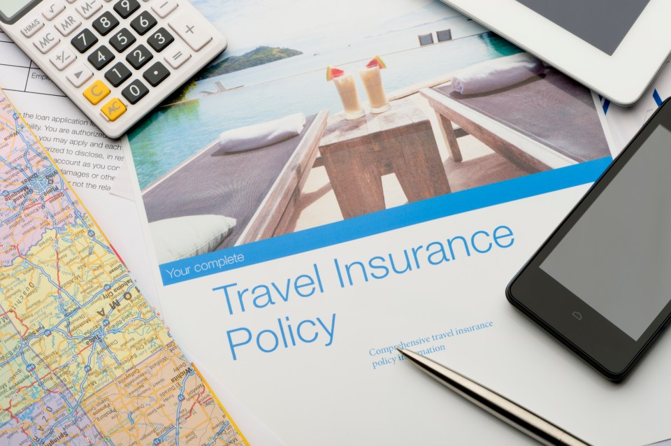 Travel insurance policy document with calculator, phone, map, and tablet.
