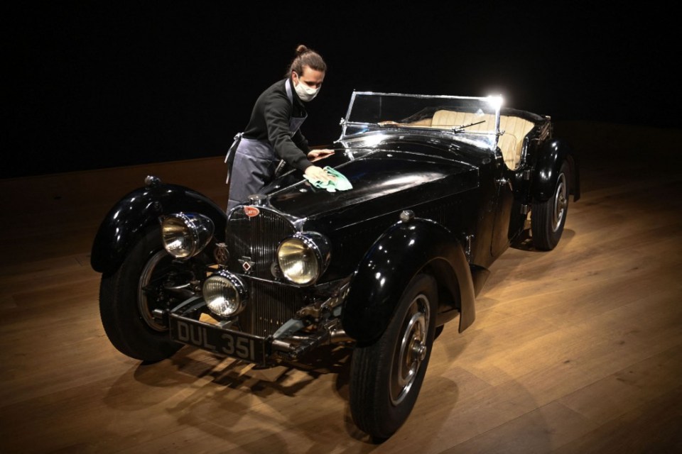 An employee poses with a 1937 Bugatti Type 57S, nicknamed 'Dulcie' due to its registration number 'DUL 351' at Bonhams in central London on February 16, 2021. - The Bugatti, which has not been seen for 50 years, is expected to realise between GBP five and seven million pounds (Euros 6-8 million, USD 7-10 million), in a sale of exceptional motor cars on February 19. (Photo by Daniel LEAL / AFP) (Photo by DANIEL LEAL/AFP via Getty Images)