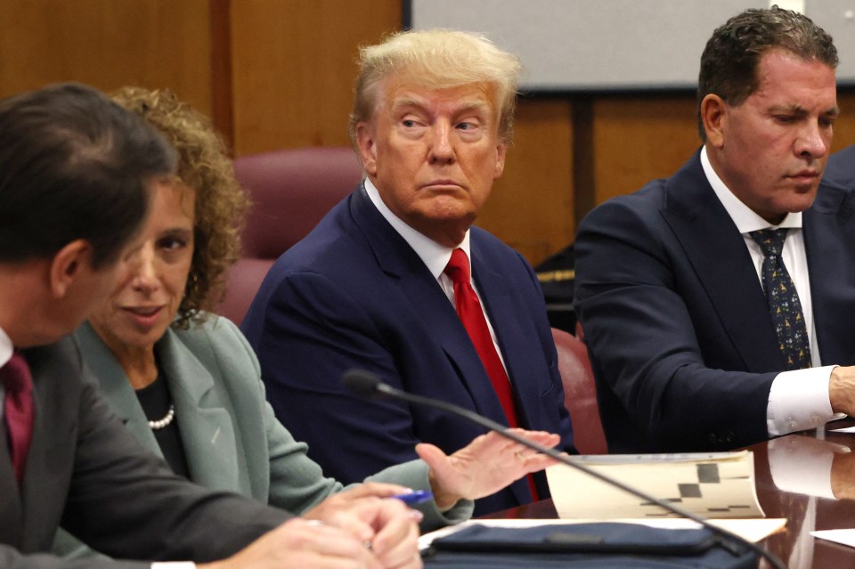 He sits with members of his legal team at the hearing in Manhatten