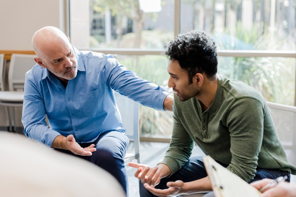 a man in a blue shirt is talking to another man in a green shirt