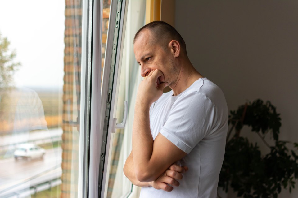 a man in a white shirt is looking out a window