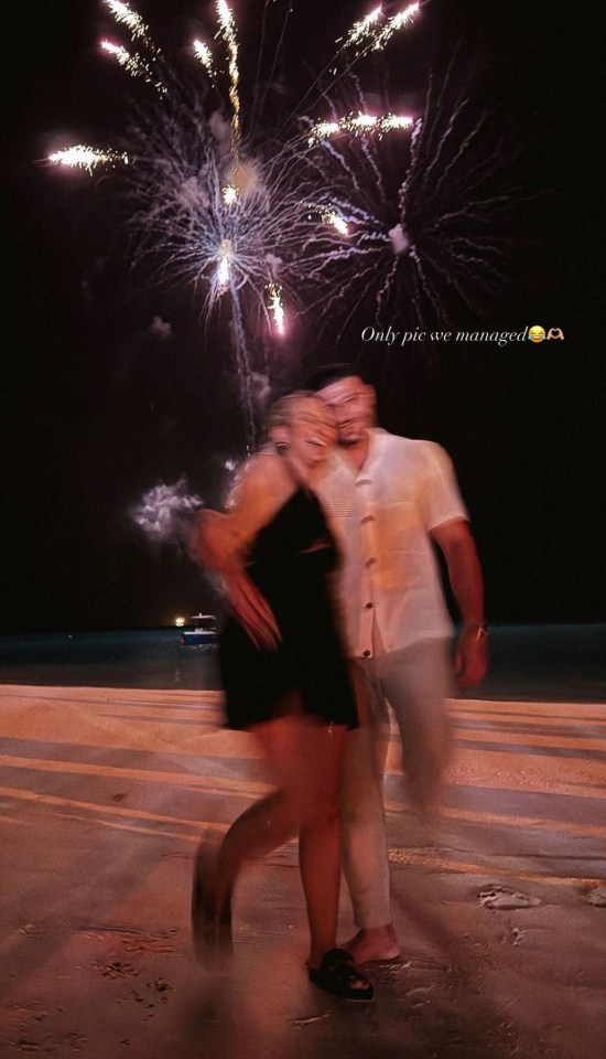 a blurry photo of a man and woman standing in front of fireworks with the caption only pic we managed