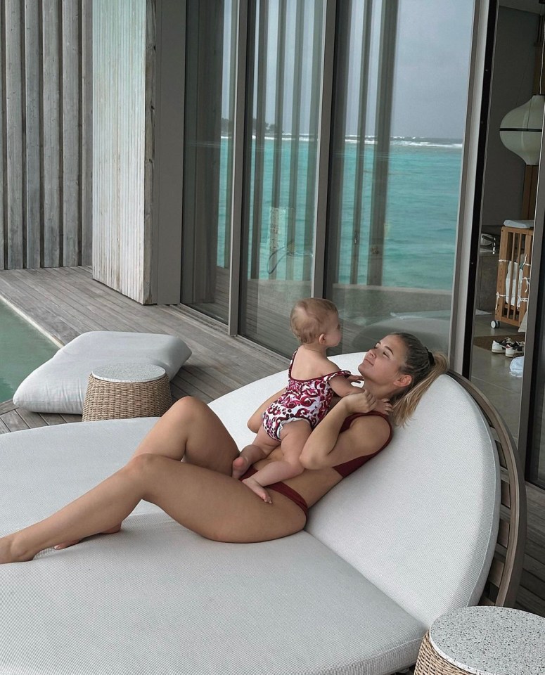 a woman in a bikini is laying on a couch holding a baby