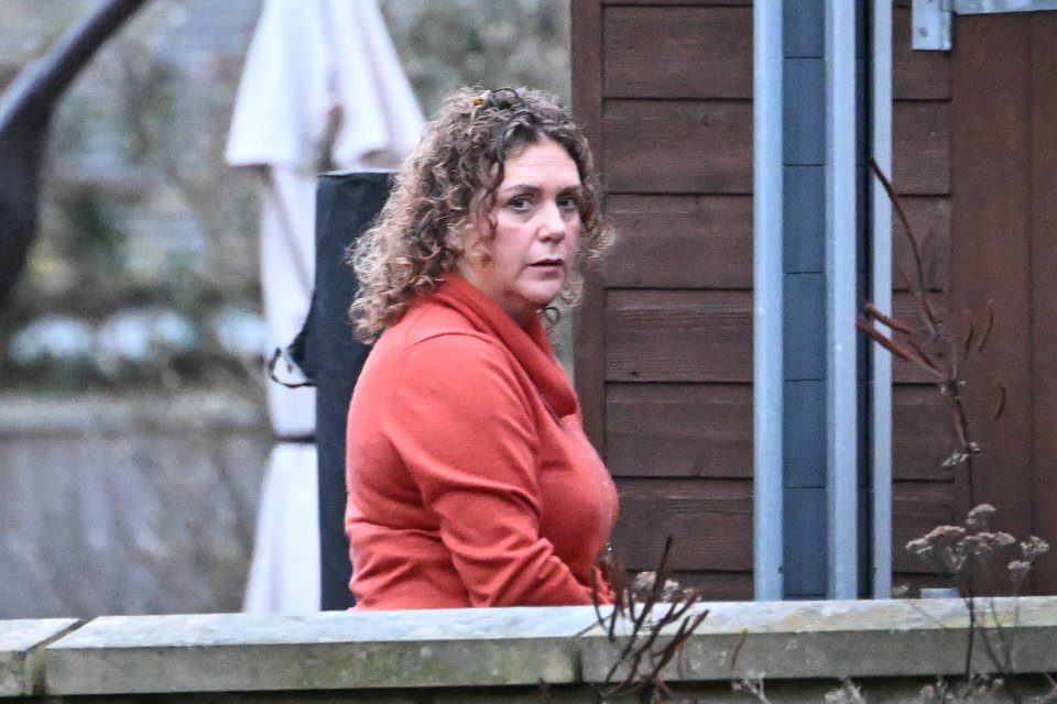 a woman with curly hair is standing in front of a wooden building