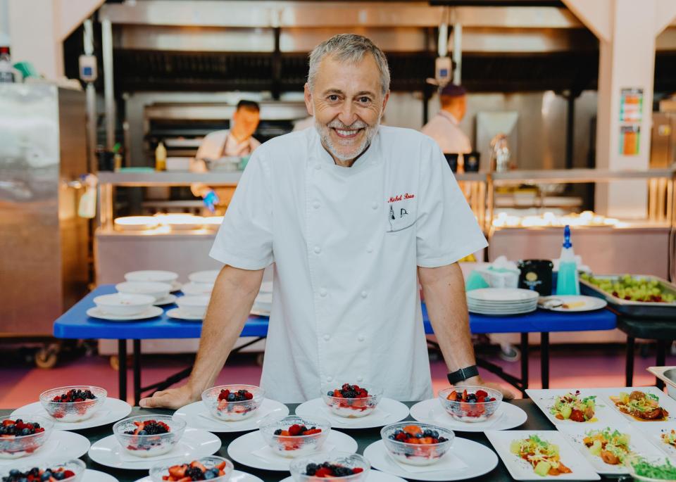 a man in a chef 's uniform stands in front of plates of food