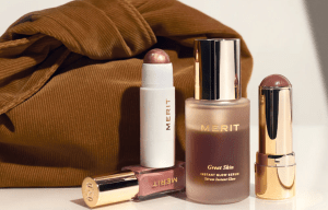 Merit makeup products: serum, lip gloss, and two glow sticks.