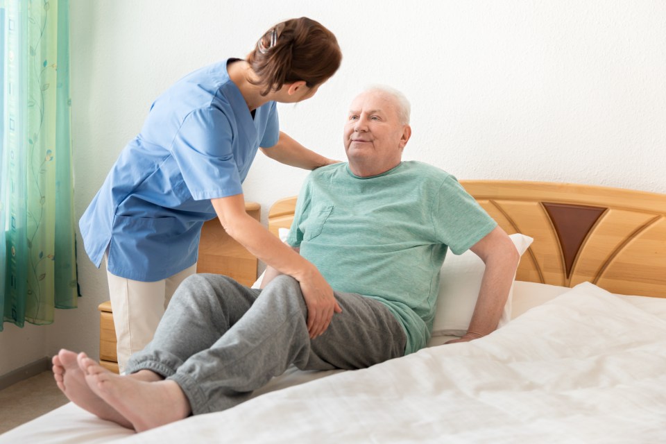 Nursing home  home caregiver helping an elderly man out of bed