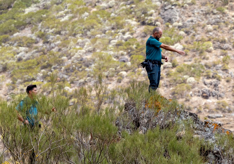 a man in a blue shirt is standing on top of a hill