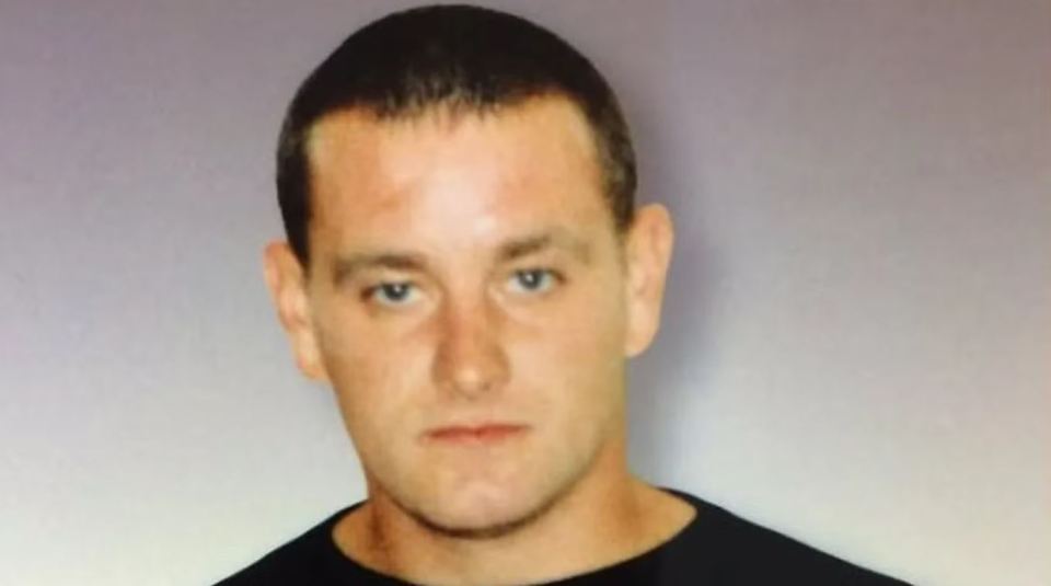 the man is wearing a black shirt and looking at the camera .