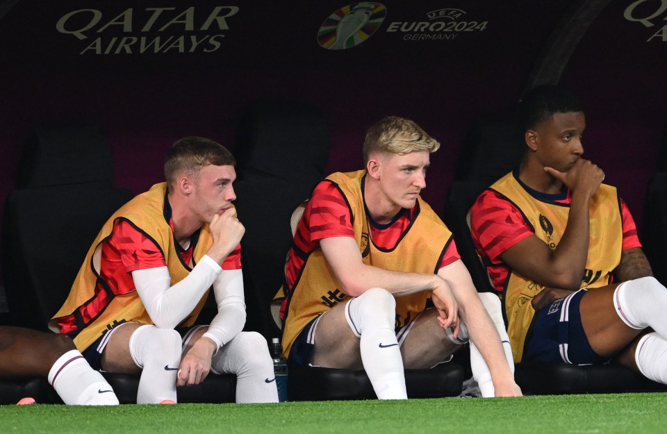 a group of soccer players sit on a bench in front of an ad for qatar airways