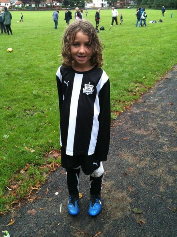 a young boy wearing a black and white striped shirt with the word soccer on it