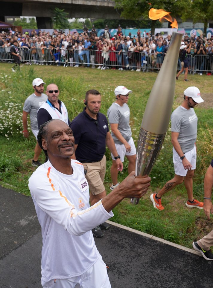 snoop dogg is holding a torch in front of a crowd