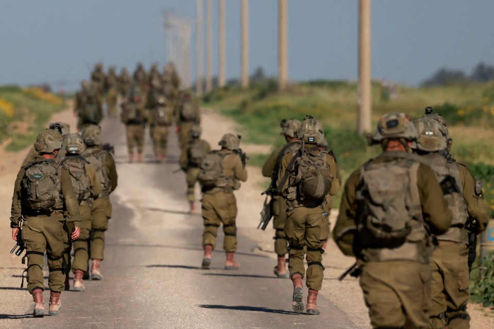 Israeli soldiers walk after coming out from the Gaza Strip, near the border in southern Israel on March 12, 2024, amid the ongoing battles between Israel and the Palestinian militant group Hamas. (Photo by Menahem KAHANA / AFP) (Photo by MENAHEM KAHANA/AFP via Getty Images)