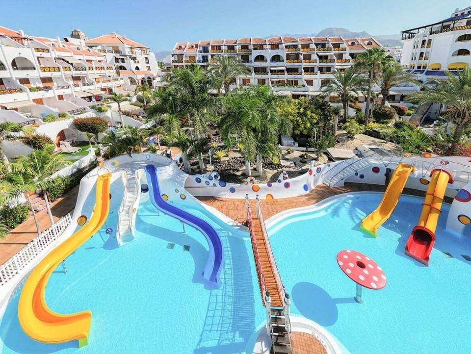 a swimming pool with water slides and a building in the background
