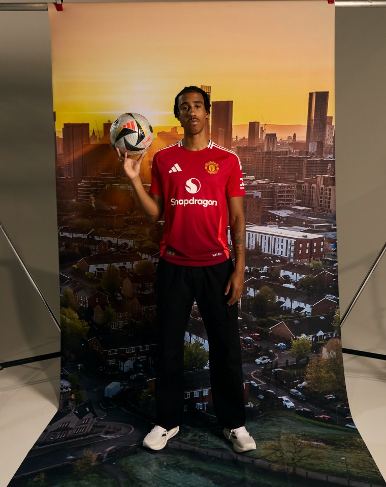 a man in a red shirt that says snapdragon holds a soccer ball
