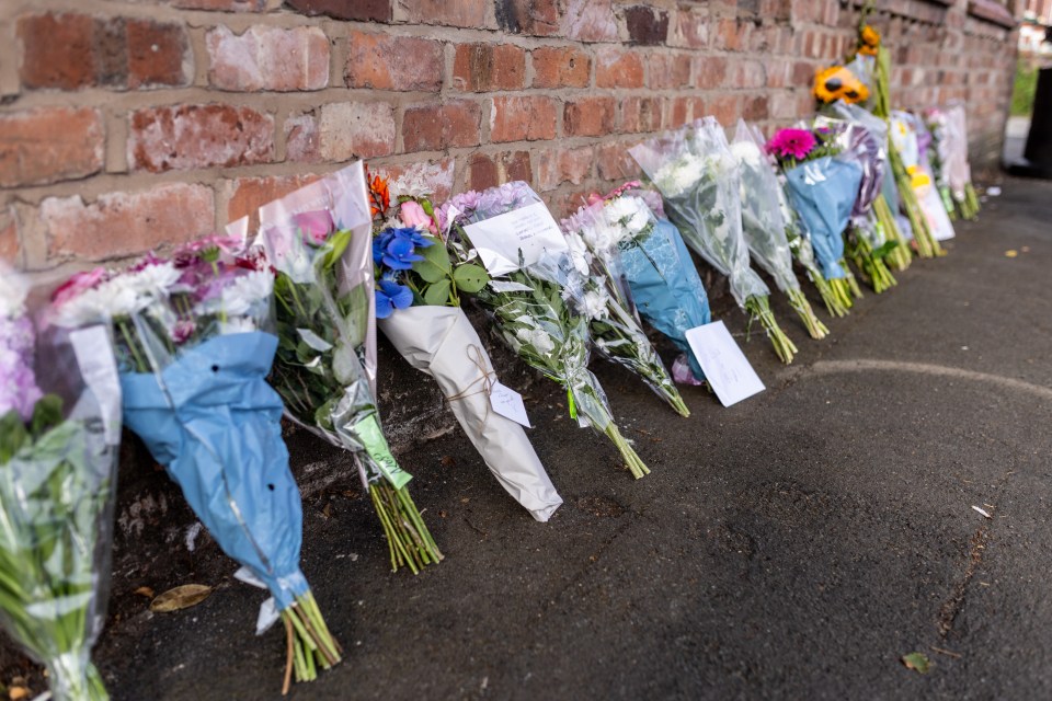 a bunch of flowers are lined up in front of a brick wall