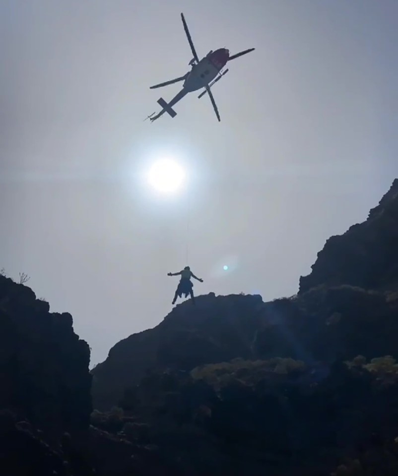 a helicopter is flying over a person on a mountain