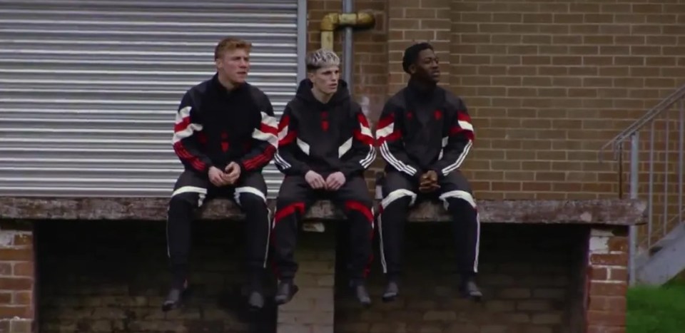 three soccer players are sitting on a brick wall