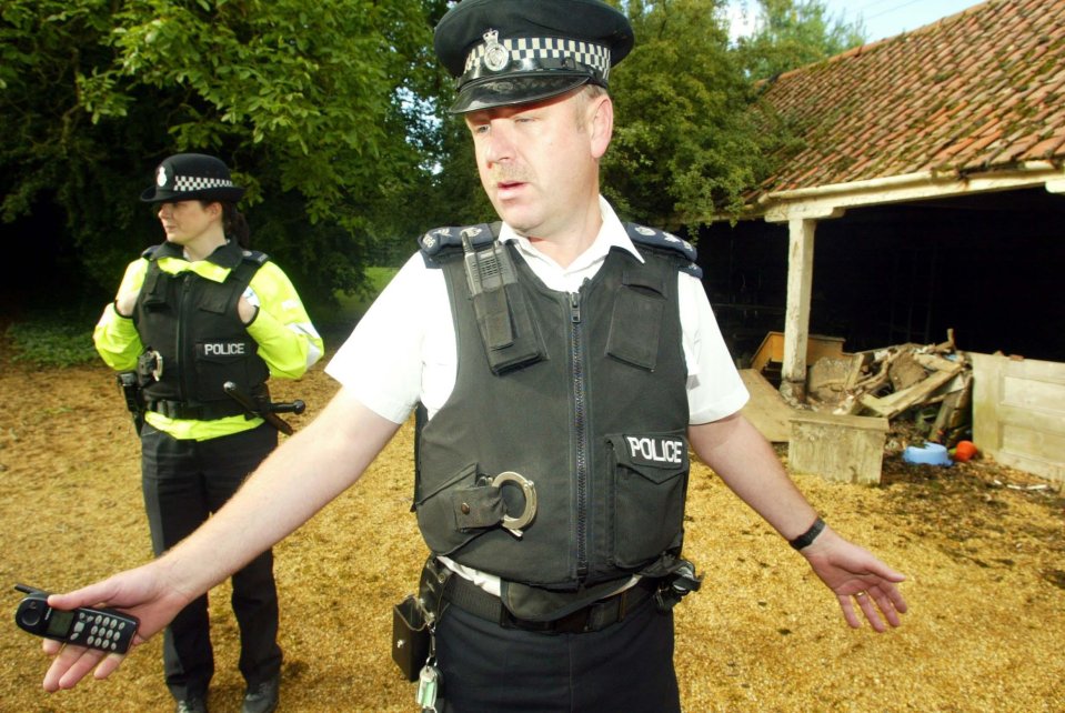 a man in a police vest is holding a cell phone