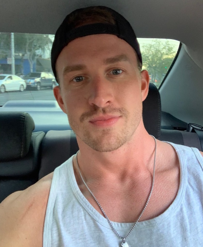 a man wearing a hat and a tank top is sitting in a car