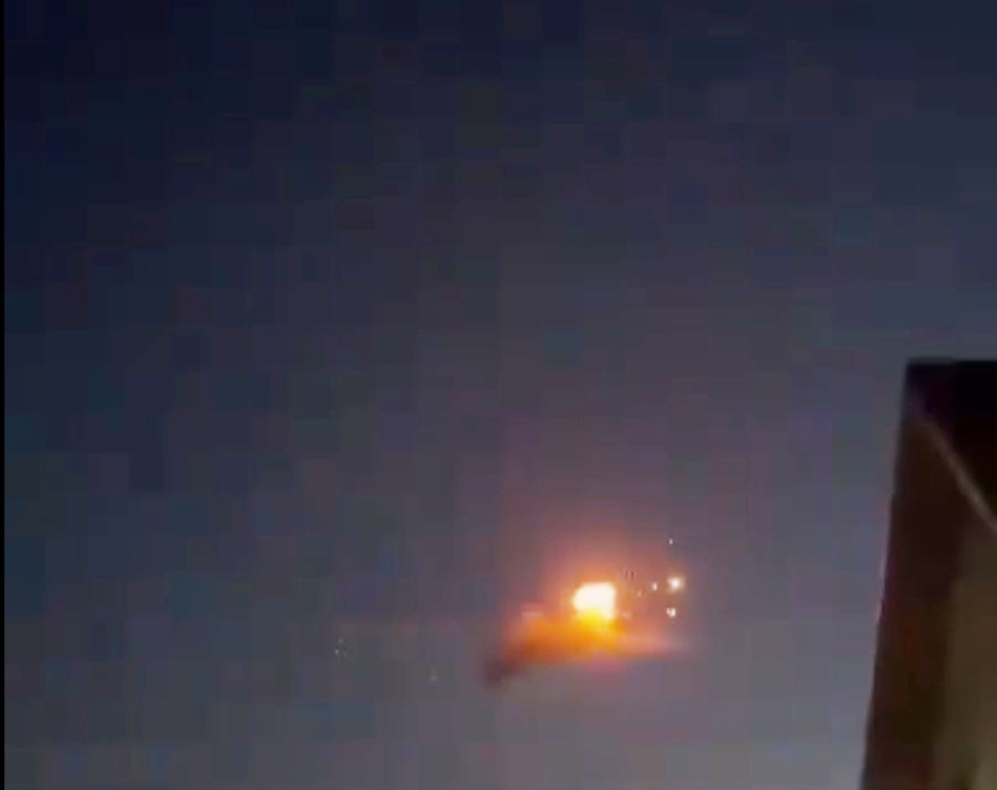 a fireball is flying in the night sky above a building .