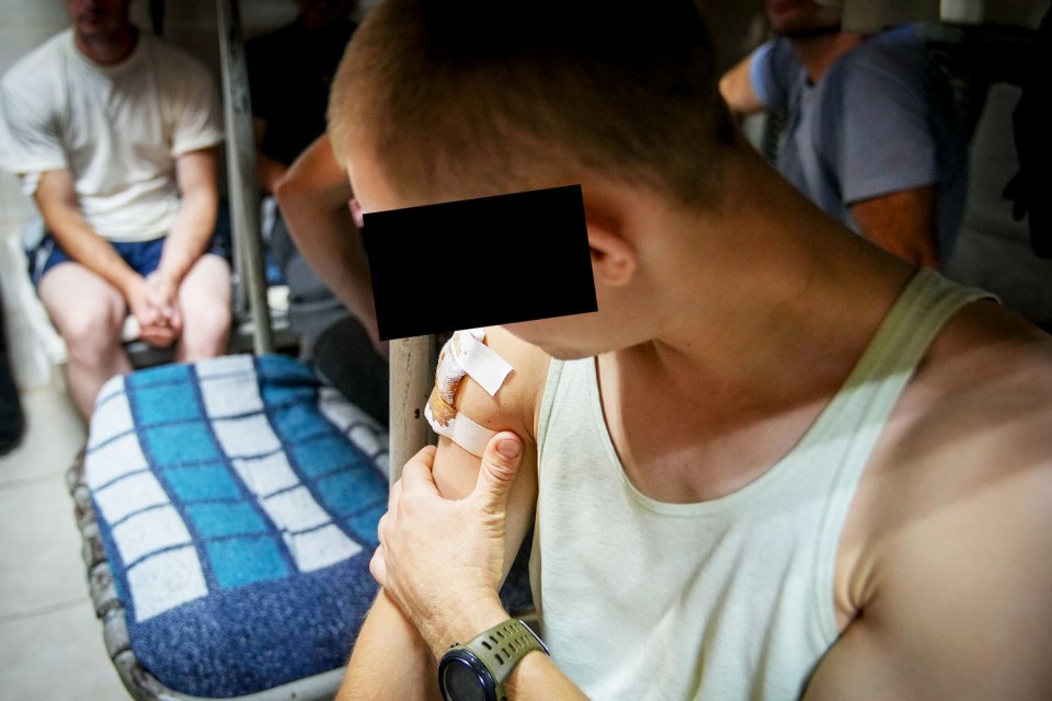 a man in a white tank top has a bandage on his arm