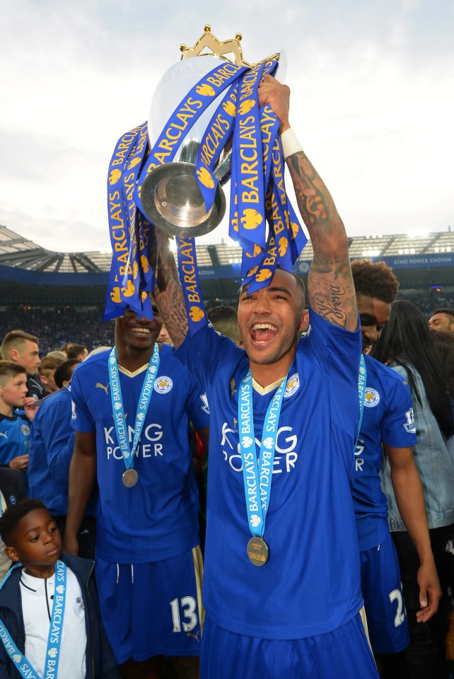 a man in a blue shirt with the number 13 on it holds up a trophy