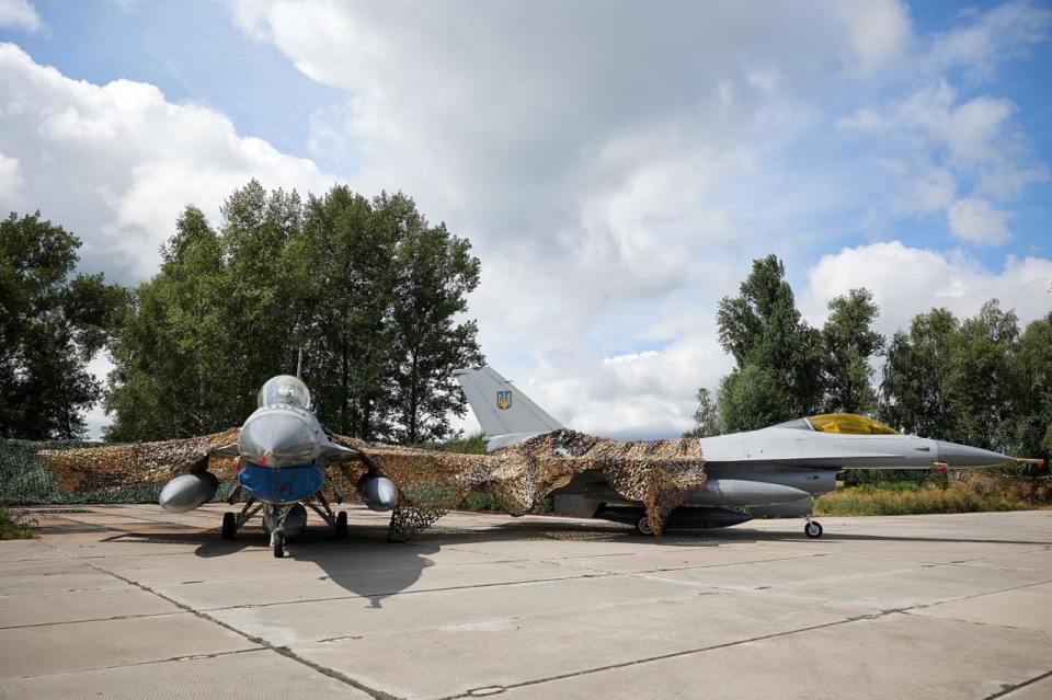 a fighter jet is parked on a runway with trees in the background