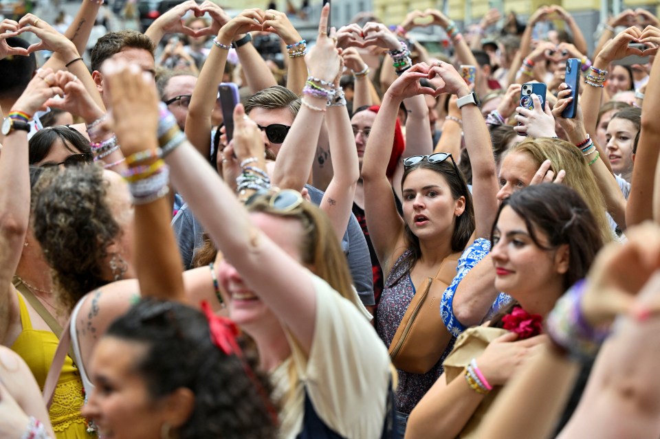 a crowd of people are making heart shapes with their hands
