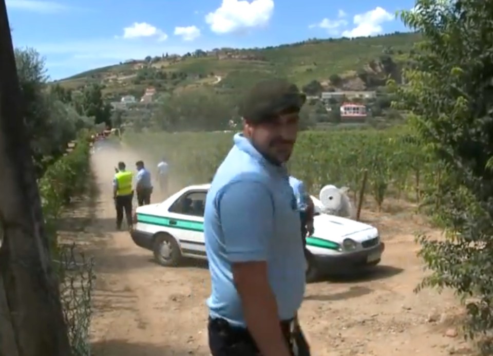 a man in a blue shirt stands in front of a police car
