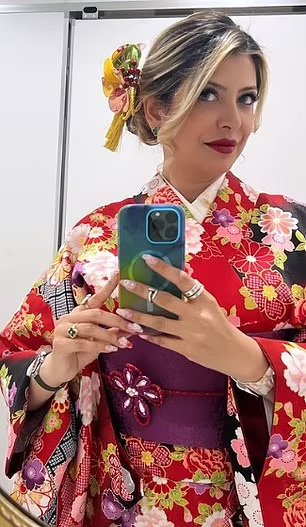 a woman in a red kimono is taking a selfie in front of a mirror .