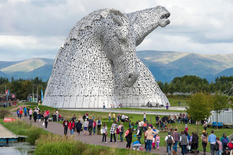 a large statue of a horse is surrounded by people