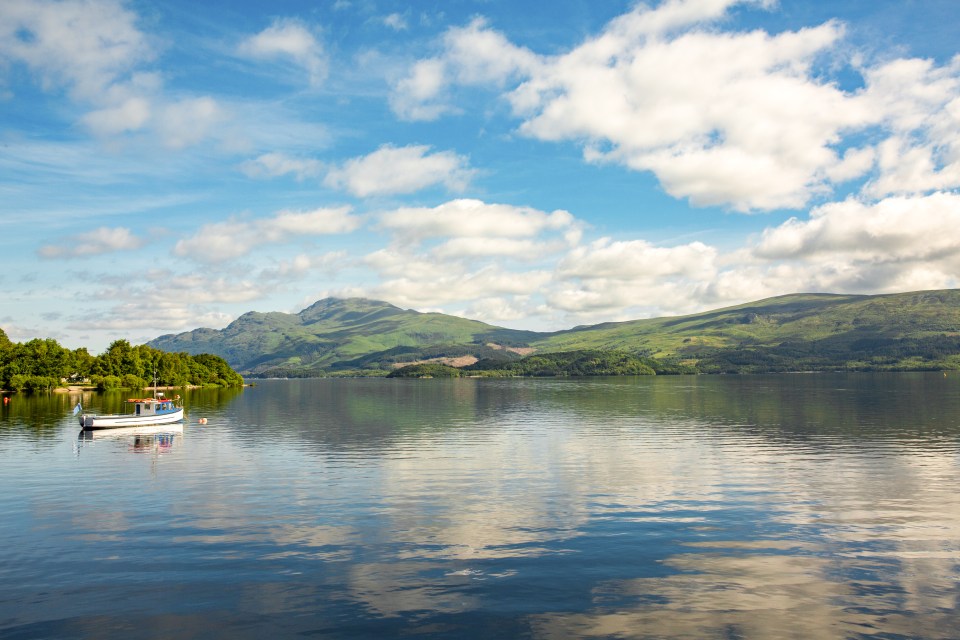 a boat is floating on a lake with mountains in the background