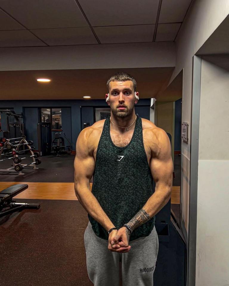 a man in a gym wearing a tank top with the letter g on it