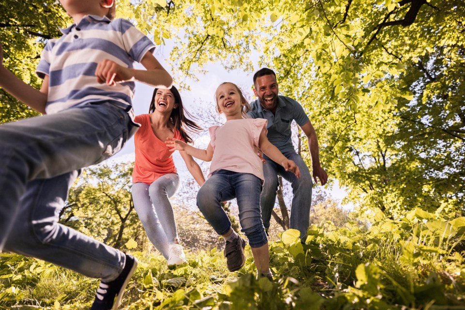 a family is running through a park holding hands