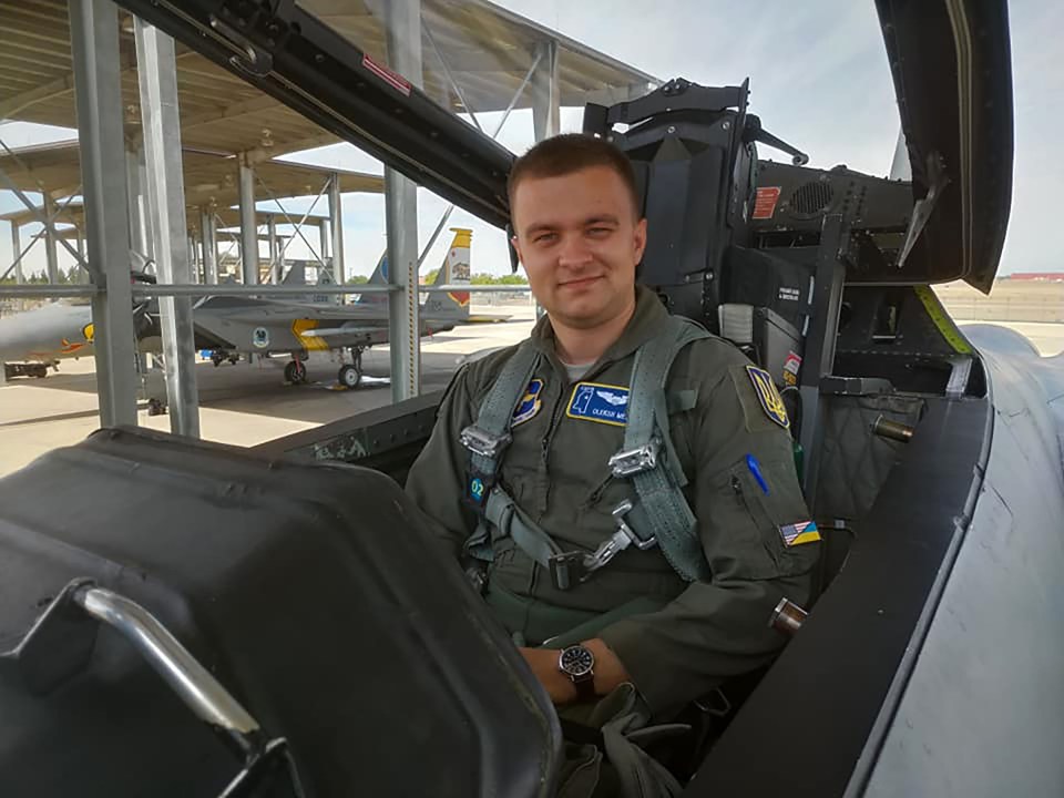a man in a military uniform is sitting in the cockpit of a fighter jet