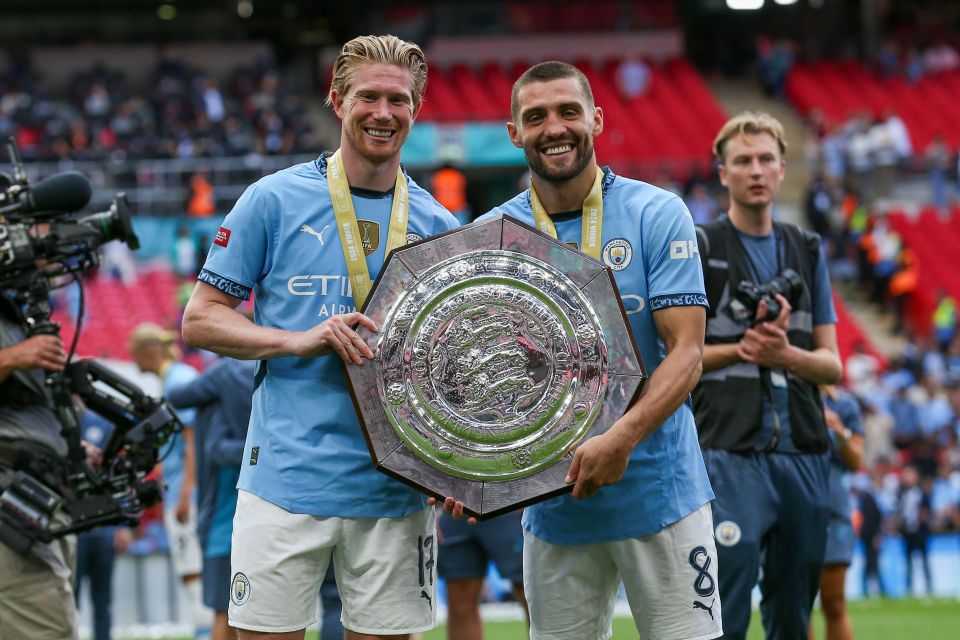 two soccer players holding a trophy and one has the number 8 on his shorts
