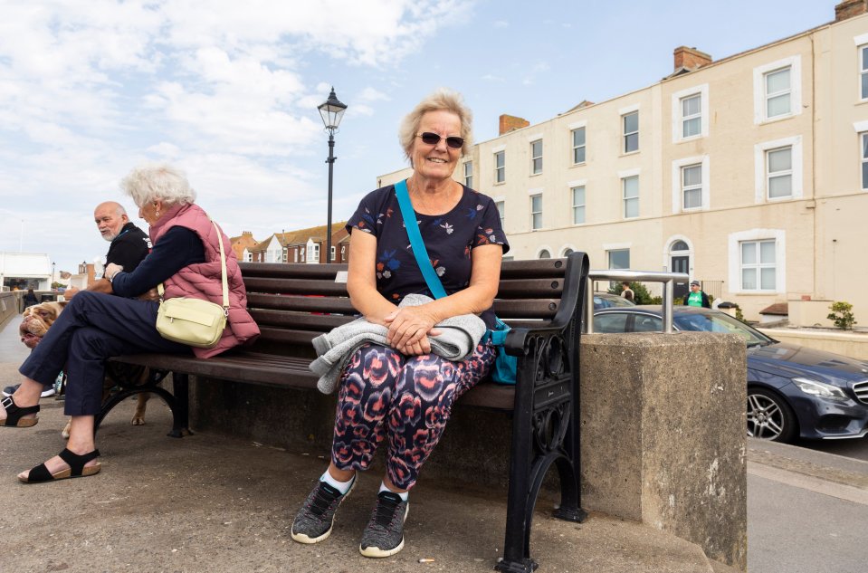 a woman sits on a bench in front of a building