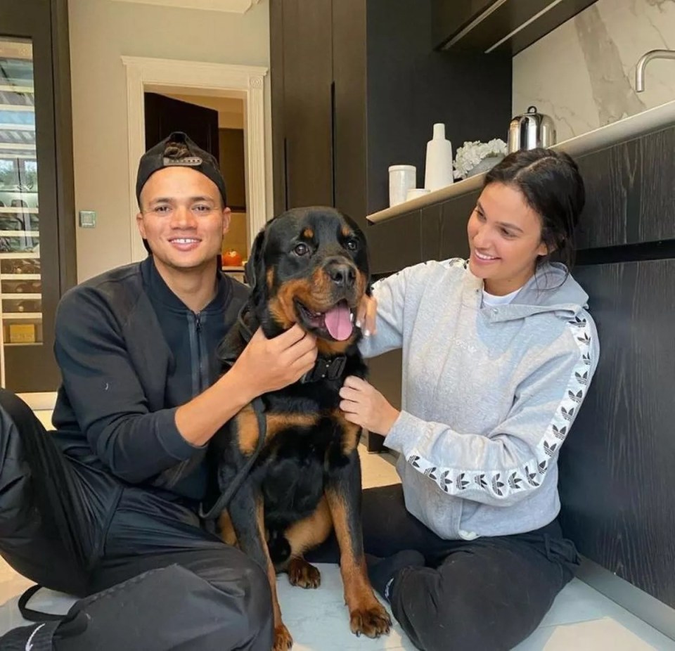 a man and a woman are petting a dog in a kitchen