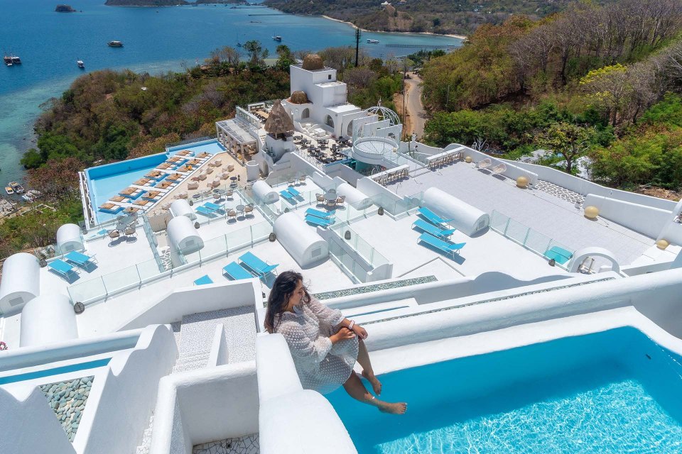 a woman sits on the edge of a swimming pool