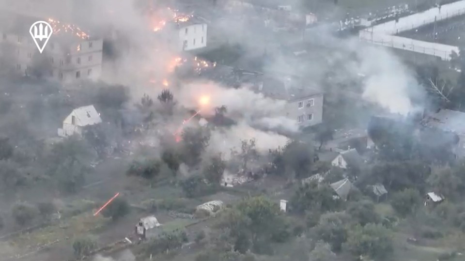 an aerial view of a fire in a village with a russian symbol